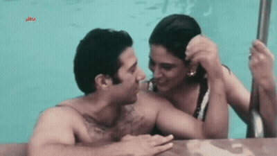 A Man And Woman Are Kissing In A Pool . GIF