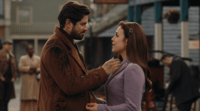 A Man And Woman Are Kissing In Front Of A Crowd Of People GIF