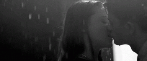 A Man And Woman Are Kissing In The Rain . GIF