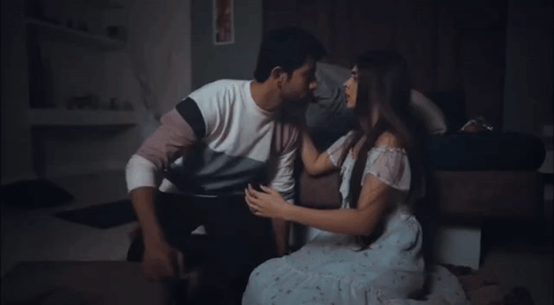 A Man And Woman Are Kissing On The Floor In A Dark Room . GIF