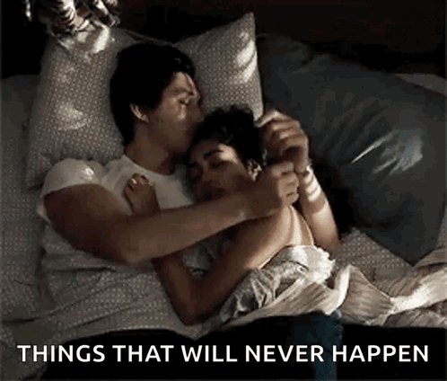 A Man And Woman Are Laying In Bed Hugging And Kissing . GIF