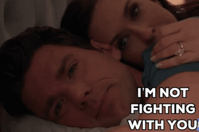 A Man And Woman Are Laying On A Bed With The Words I 'M Not Fighting With You GIF