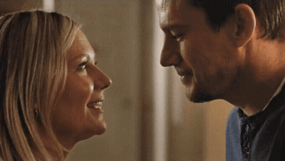 A Man And Woman Are Looking At Each Other And Smiling GIF