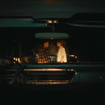 A Man And Woman Are Looking At Each Other In A Car GIF