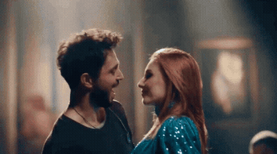 A Man And Woman Are Looking At Each Other In A Dark Room . GIF