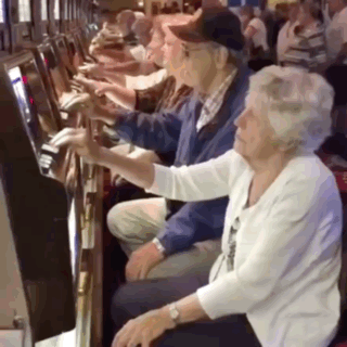 A Man And Woman Are Playing A Slot Machine In A Casino GIF