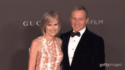 A Man And Woman Are Posing For A Picture In Front Of A Wall That Says Gucci Film GIF