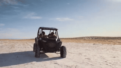 A Man And Woman Are Riding A Polaris Atv In The Desert GIF
