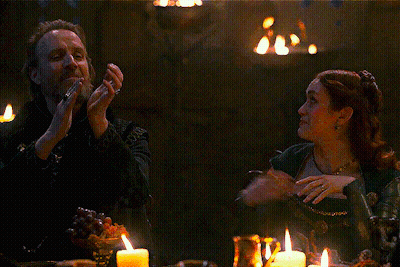 A Man And Woman Are Sitting At A Table With Candles GIF