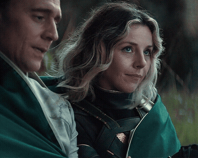 A Man And Woman Are Standing Next To Each Other And The Woman Is Smiling GIF