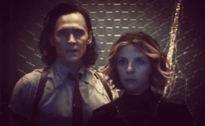 A Man And Woman Are Standing Next To Each Other In A Dark Room . GIF