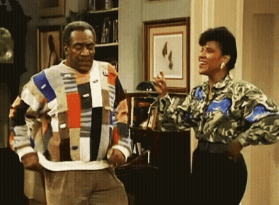 A Man And Woman Are Standing Next To Each Other In A Living Room GIF