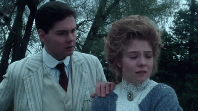 A Man And Woman Are Standing Next To Each Other In A Park . GIF