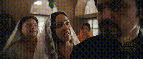 A Man And Woman Are Standing Next To Each Other In A Room . The Woman Is Wearing A Veil . GIF