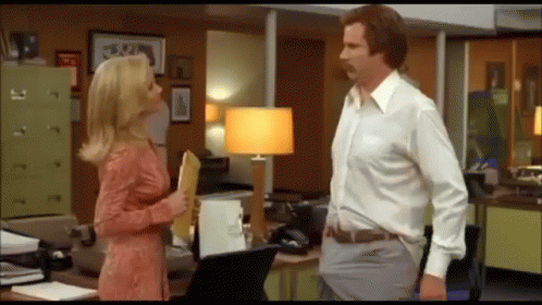 A Man And Woman Are Standing Next To Each Other In An Office . GIF