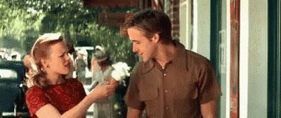 A Man And Woman Are Standing Next To Each Other On A Sidewalk . GIF