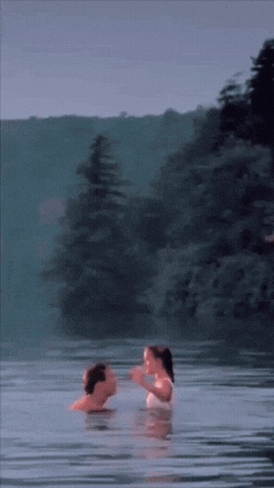 A Man And Woman Are Swimming In A Lake GIF