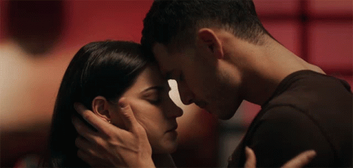 A Man And Woman Are Touching Their Foreheads In A Close Up GIF