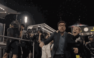 A Man And Woman Are Walking In Front Of A Sign That Says Rolex GIF