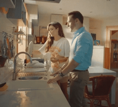 A Man And Woman Are Washing Dishes In A Kitchen Sink GIF