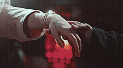 A Man And Woman Holding Hands In Front Of A Candle GIF