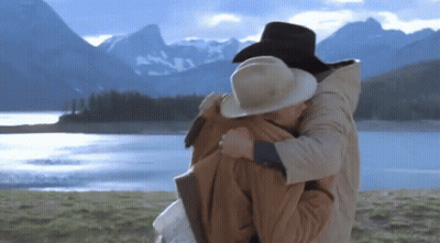 A Man And Woman Hugging In Front Of A Lake GIF