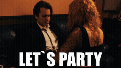 A Man And Woman Sitting On A Couch With The Words Let 'S Party GIF