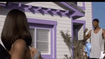 A Man And Woman Standing In Front Of A Purple House GIF