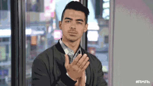 A Man Applauds In Front Of A Window With The Hashtag #Ama5 On The Bottom GIF