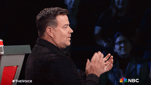 A Man Applauds While Sitting In Front Of A Screen That Says Nbc GIF