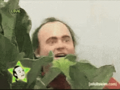 A Man Behind A Plant With A Star In The Corner That Says " Live " GIF