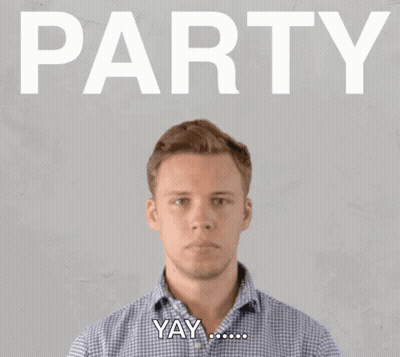 A Man Blowing Confetti In Front Of A Sign That Says Party GIF