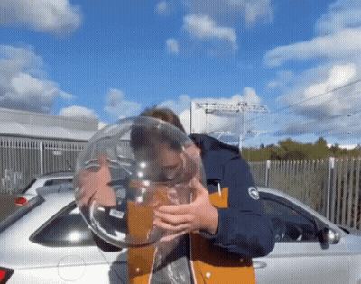 A Man Blowing Up A Balloon In Front Of A Car GIF