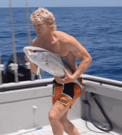 A Man Carrying A Large Fish On A Boat In The Ocean GIF
