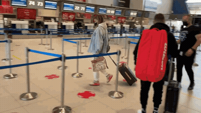 A Man Carrying A Red Bag With The Word Wilson On It Walks Through An Airport GIF