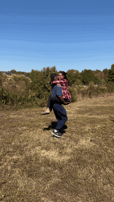 A Man Carrying A Woman In His Arms In A Field GIF