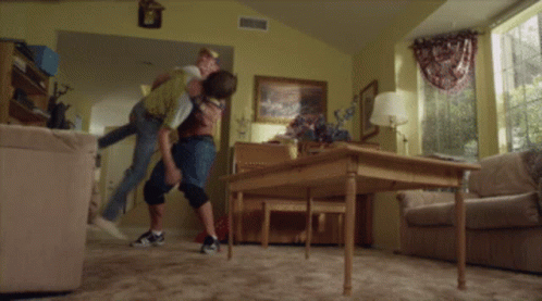 A Man Carrying Another Man In A Living Room GIF