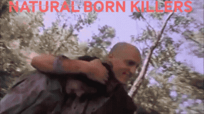 A Man Carrying Another Man With The Words Natural Born Killers Written On The Bottom GIF