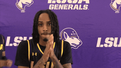 A Man Clapping In Front Of A Purple Banner That Says Lsu GIF