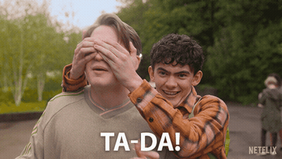 A Man Covering Another Man 'S Eyes With His Hands And The Words Ta-Da Are Visible GIF