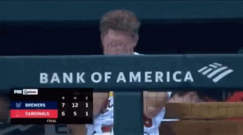 A Man Covering His Face In Front Of A Bank Of America Banner GIF