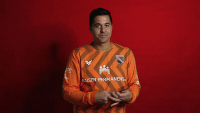 A Man Covering His Face While Holding A Card That Says Kaiser Permanent GIF