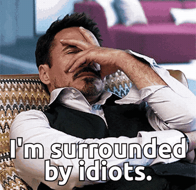 A Man Covering His Face With His Hand And The Words " I 'M Surrounded By Idiots " GIF