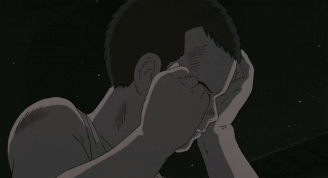 A Man Covering His Face With His Hand In A Dark Room GIF