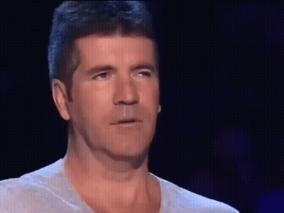 A Man Covering His Face With His Hand In Front Of A Dark Background GIF