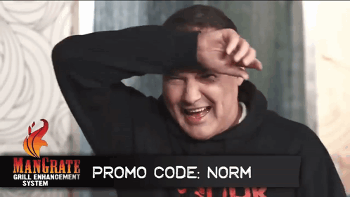A Man Covering His Face With His Hand In Front Of A Sign That Says Mangrate Grill Enhancement System GIF
