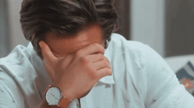 a man covering his face with his hand wearing a watch