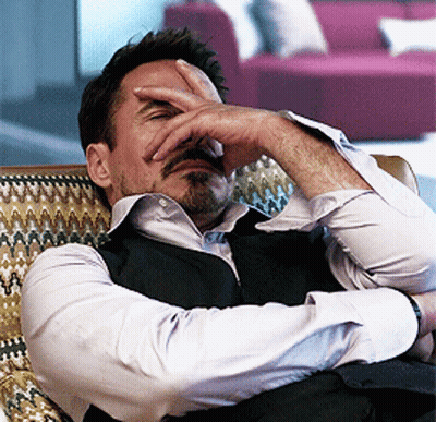 A Man Covering His Face With His Hand While Sitting On A Chair GIF