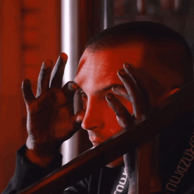 A Man Covering His Face With His Hands And A Black Shirt With The Word Tour On The Back GIF