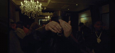 A Man Covering His Face With His Hands In A Dark Room With A Chandelier GIF